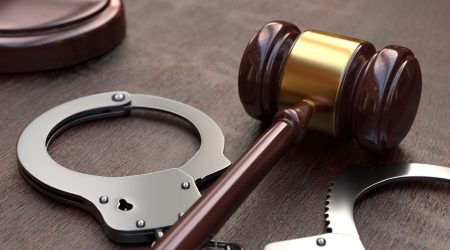 Gavel and handcuffs on wooden, brown table background